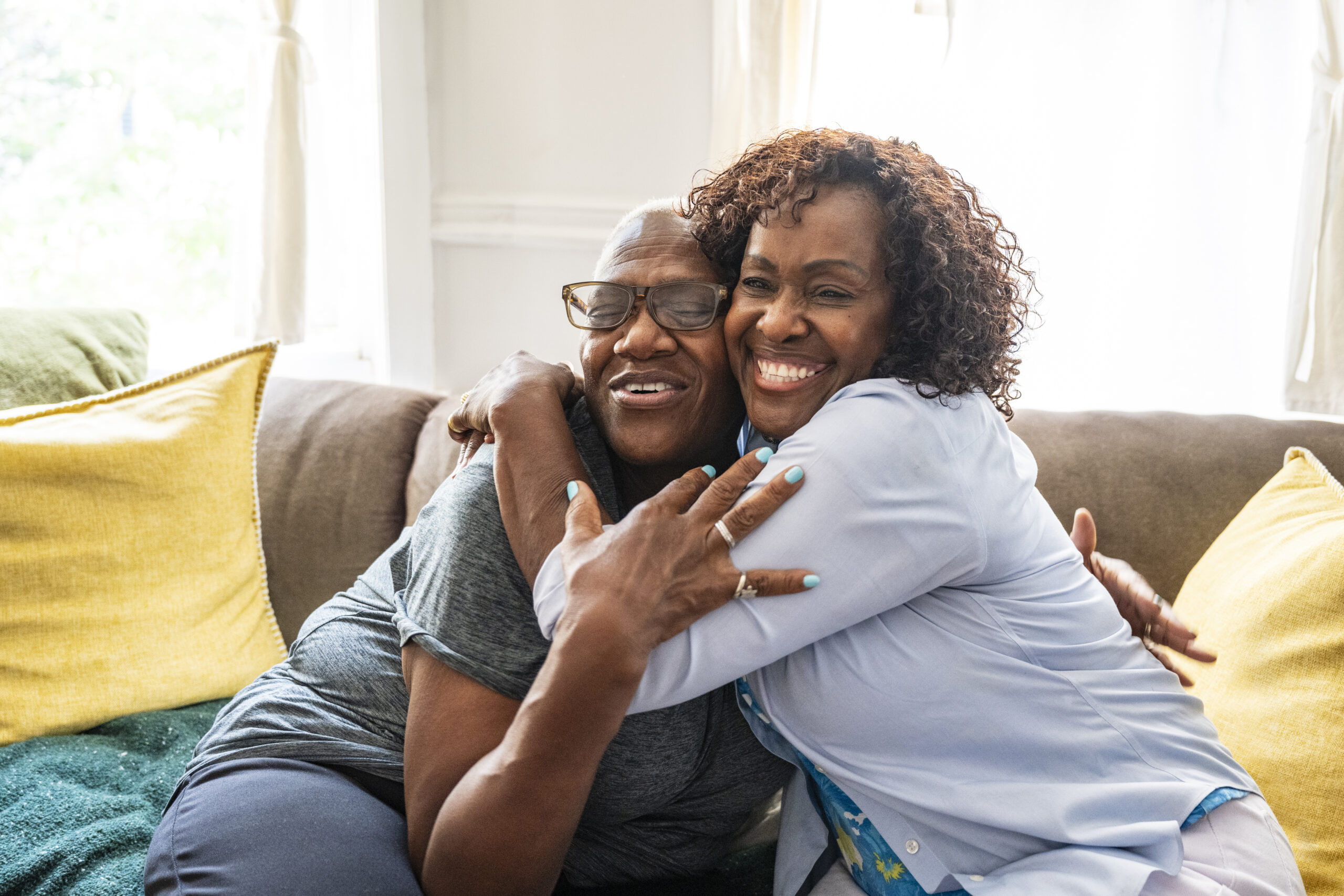 Mother and daughter sharing love and joy Two people sitting on a couch, smiling and embracing.
